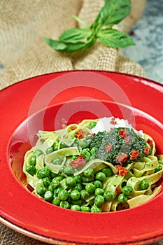 Spaghetti with fresh green peas. Gray textured background with beige fabric. Beautiful serving of dishes. Restaurant