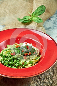 Spaghetti with fresh green peas. Gray textured background with beige fabric. Beautiful serving of dishes. Restaurant