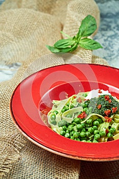 Spaghetti with fresh green peas. Gray textured background with beige fabric. Beautiful serving of dishes. Restaurant