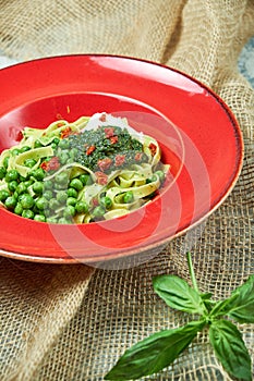 Spaghetti with fresh green peas. Gray textured background with beige fabric. Beautiful serving of dishes. Restaurant