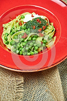 Spaghetti with fresh green peas. Gray textured background with beige fabric. Beautiful serving of dishes. Restaurant