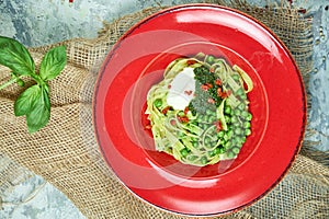 Spaghetti with fresh green peas. Gray textured background with beige fabric. Beautiful serving of dishes. Restaurant