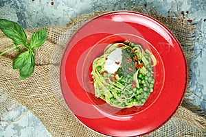 Spaghetti with fresh green peas. Gray textured background with beige fabric. Beautiful serving of dishes. Restaurant