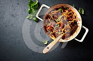 Spaghetti with fresh Tomato Sauce, Kalamata Olives and Basil in a Cooking Pan seen from above