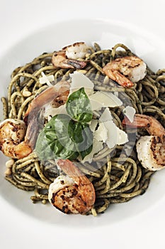 Spaghetti gamberi pasta with prawns and pesto on white background photo