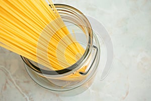 Spaghetti in glass jar and copy space. Ingredient for Italian pasta. Raw food and cookware