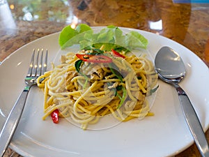 The Spaghetti , green curry with pork on a white plate. on the wooden table.