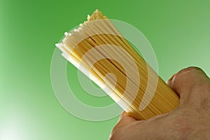 Spaghetti in humand hand on green background