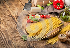 Spaghetti with ingredients for cooking pasta on round wooden boa