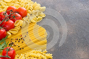 Spaghetti with ingredients for cooking pasta on a stone dark background, top view