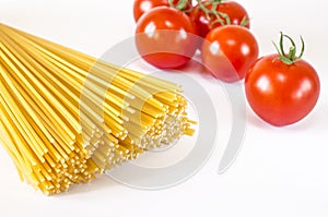 Spaghetti lie on a white background, along with cherry tomatoes