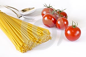 Spaghetti lie on a white background, along with cherry tomatoes