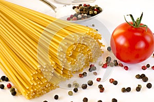 Spaghetti lie on a white background, along with cherry tomatoes