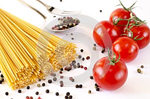 Spaghetti lie on a white background, along with cherry tomatoes