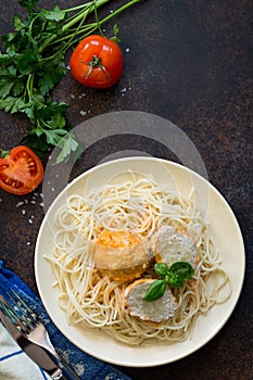 Spaghetti with meatballs and broccoli filling on a stone table.