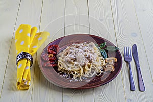 Spaghetti with mushrooms in cream sauce on a yellow wooden background.