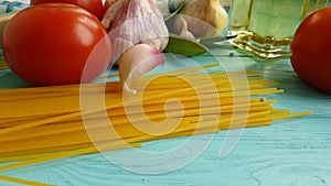 Spaghetti, oil healthy food preparatio dinner , vegetarian slow-motion garlic tomato black pepper on a blue wooden background