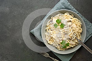 Spaghetti pasta with creamy mushroom sauce on a dark painted background. Italian traditional dish. Top view, copy space