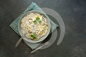 Spaghetti pasta with creamy mushroom sauce on a dark painted background. Italian traditional dish. Top view, copy space