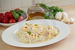 Spaghetti pasta with garlic, olive oil, chilly peppers and basil herbs. Ingredients on background. Close up view.