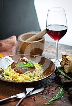 Spaghetti pasta and meat balls in tomato sauce in brown plate with Basil and Parmesan on wooden