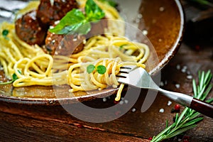 Spaghetti pasta and meat balls in tomato sauce in brown plate with Basil and Parmesan