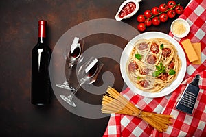 Spaghetti pasta with meatballs, cherry tomato sauce, cheese, wineglass and bottle on rusty background