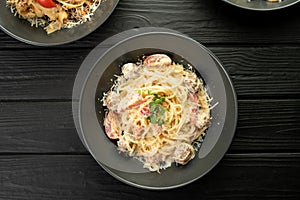 Spaghetti pasta with meatballs in a creamy sauce with Parmesan cheese and tomatoes served on a dark table. Restaurant