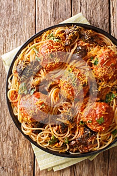 Spaghetti pasta with meatballs, mushrooms and cheddar cheese close-up in a plate. Vertical top view