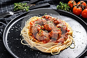 Spaghetti pasta with meatballs and tomato sauce. Italian cuisine. Black background. Top view
