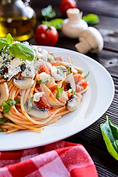 Spaghetti pasta salad with tomato sauce, mushrooms, blue cheese and basil