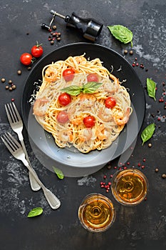 Spaghetti pasta with shrimps and white wine on a dark stone background. Top view