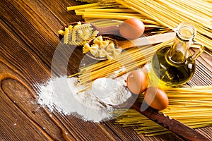 Spaghetti and pasta on a table with eggs and flour and olive oil