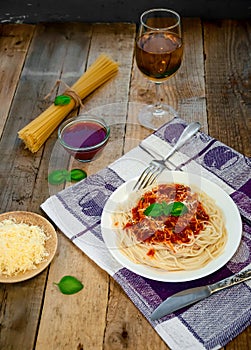 Spaghetti Pasta with Tomato Sauce, Chees and Basil with White Wine Glass on Wooden Table. Traditional Italian Food