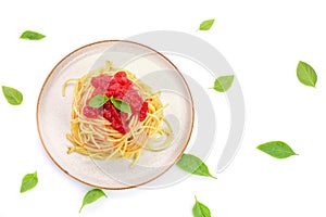 Spaghetti or pasta with tomato sauce and fresh green basil on a white plate isolated on a white background - top view