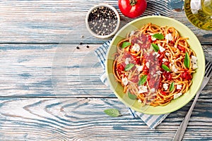 Spaghetti pasta with tomato sauce, mozzarella cheese and fresh basil leaves on white-blue vintage wooden background