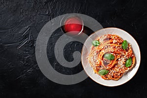 Spaghetti pasta with tomato sauce, Parmesan cheese and fresh basil leaves, shot from the top on a black background