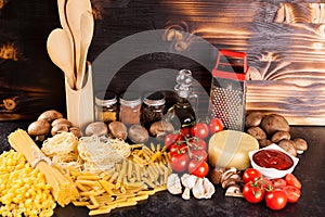 Spaghetti, pasta and uncooked macaroni next to a variety of fresh vegetables