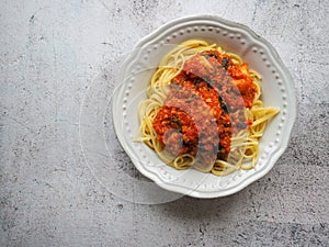 Spaghetti pasta with vegetarian soy bolognese on grey rustic background with copy space.