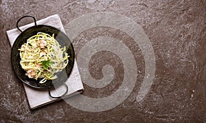 Pan of spaghetti prepared from zucchini and mushroom sauce on wooden table