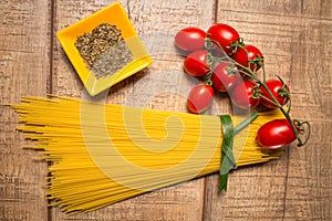 Spaghetti and Roma tomatoes isolated on wood table background. Uncooked Italian dried spaghetti. Top view.