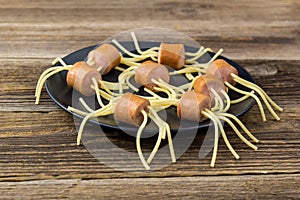 spaghetti with sausages in the form of spiders. Happy kid food for Halloween party