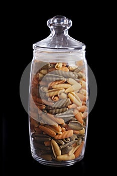 Spaghetti shells in the glass pot isolated on black