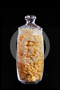 Spaghetti shells in the glass pot isolated on black