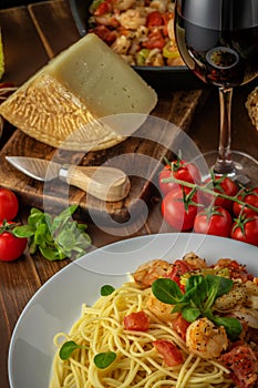 Spaghetti with shrimps, cherry tomatoes and spices on wooden background.  Food background