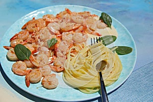 Spaghetti with shrimps in sauce on the blue plate and background photo
