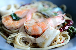 Spaghetti spicy seafood in blue dish on the table.