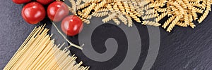 Spaghetti, spirelli and cherry tomatoes on black slate plate