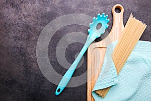 Spaghetti and spoon for spaghetti on a cutting board