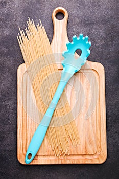 Spaghetti and spoon for spaghetti on a cutting board